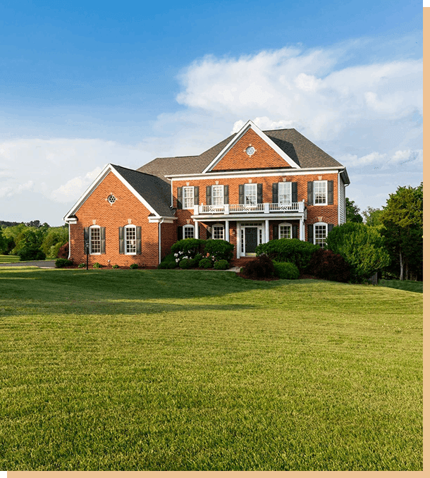 A large brick house sitting on top of a lush green field.